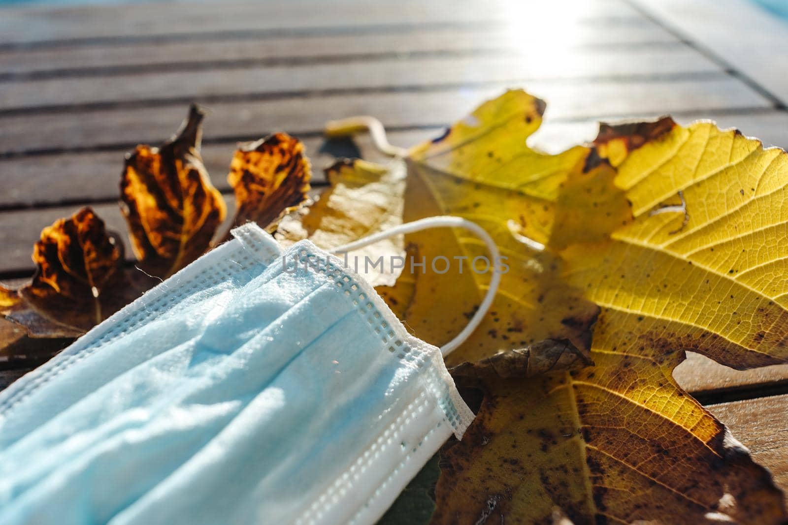 Medical mask rests on yellow autumn leaves . High quality photo