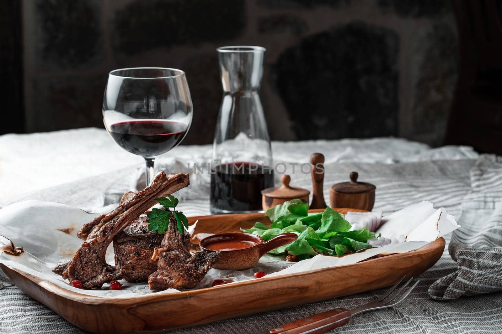 Grilled lamb loin on a wooden plate with lettuce leaves and wine. High quality photo