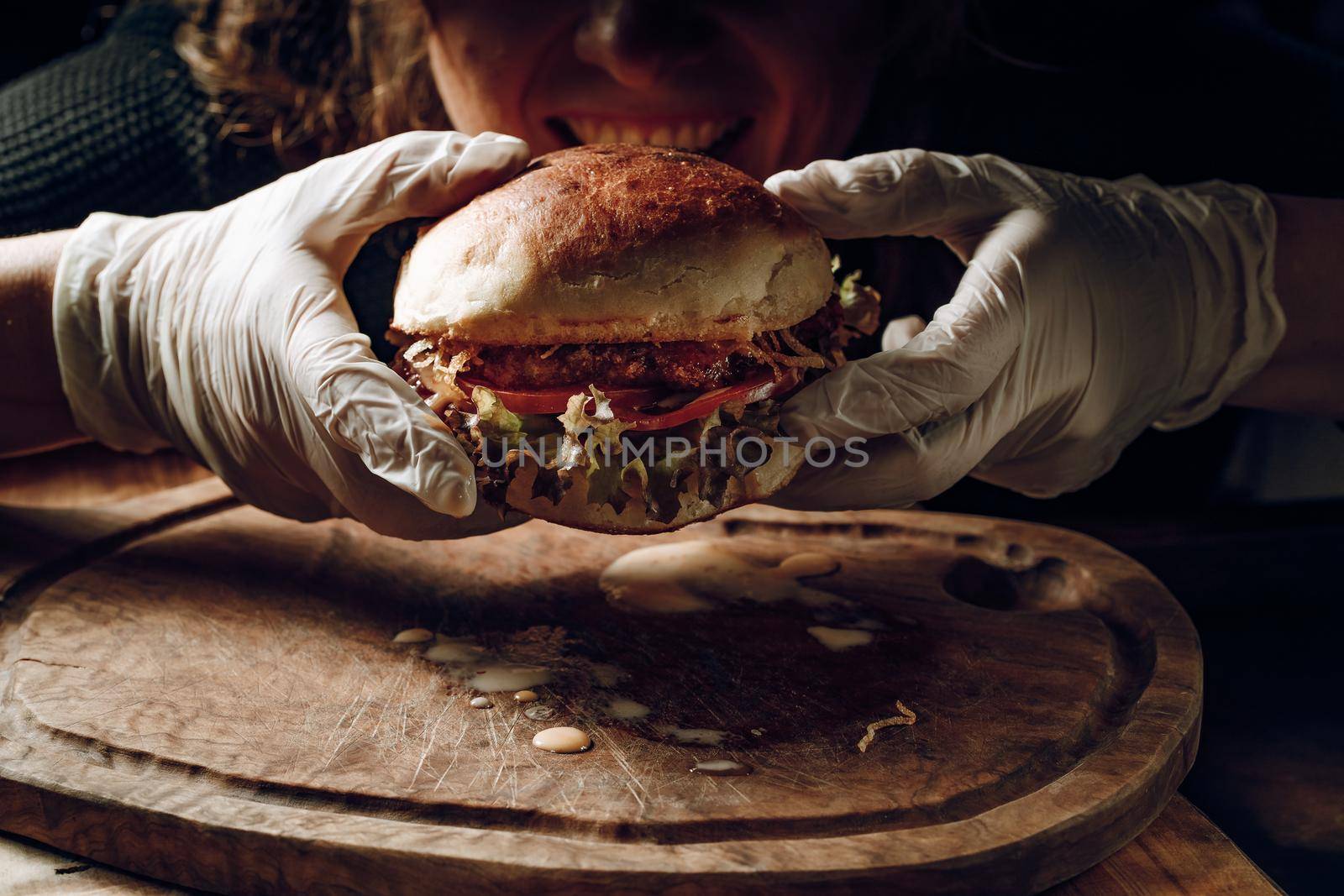 Gloved hands take a hamburer from a wooden tray. High quality photo