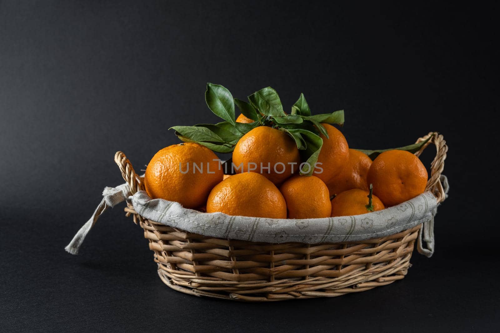 Ripe tangerines in a photo basket in the studio. High quality photo