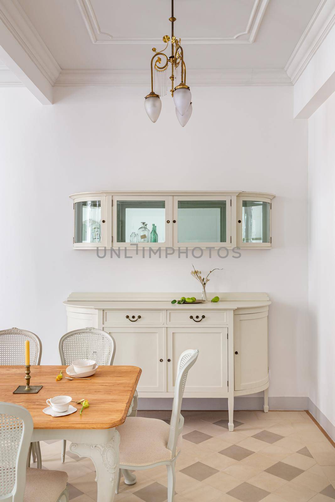 Front view of vintage style dining room with wooden table setting for two persons, tile floor and retro lamps. Refurbished apartment in Barcelona old city