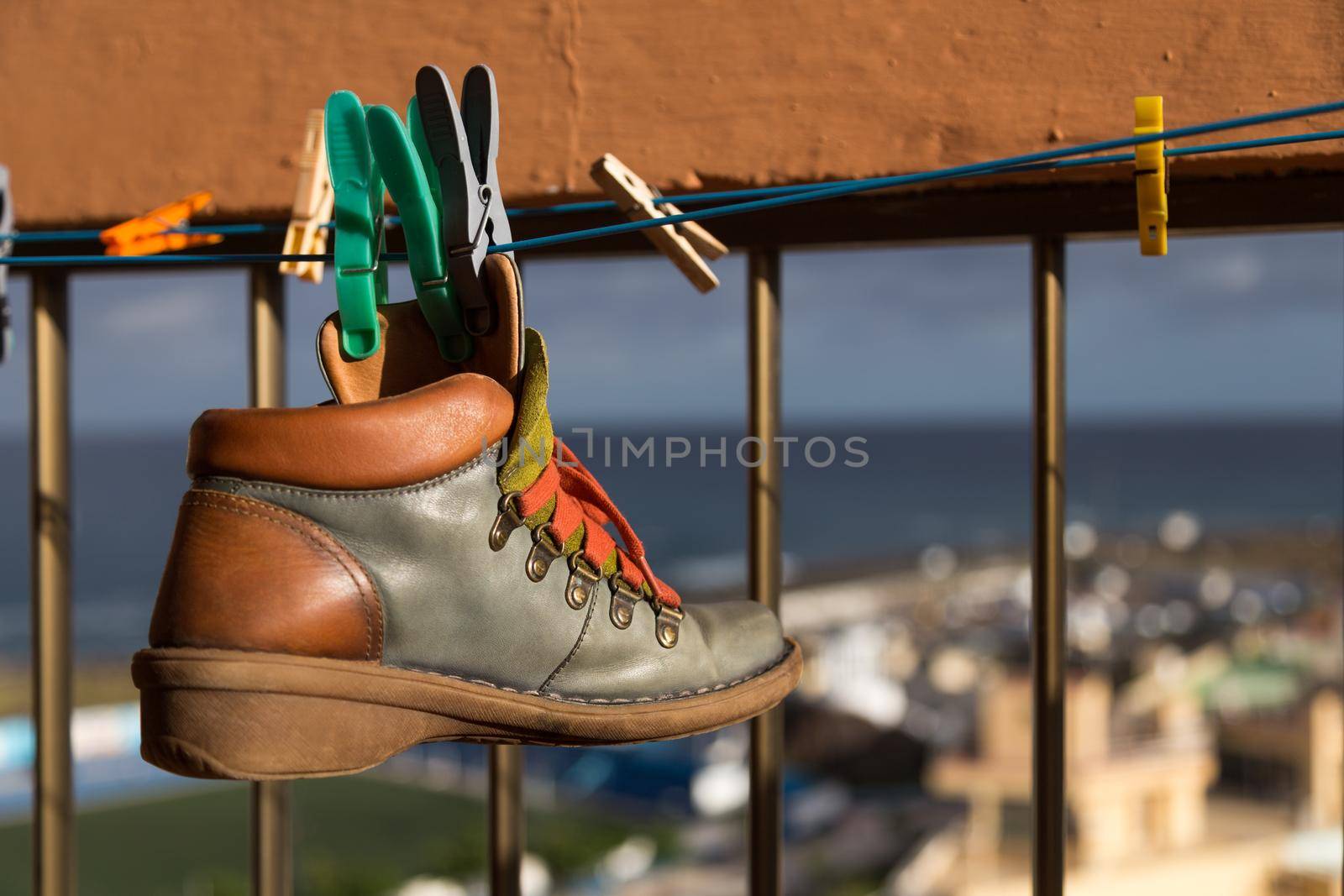Hanged with clothespins leather boot drying on a clothesline on sunny day. Selective focus