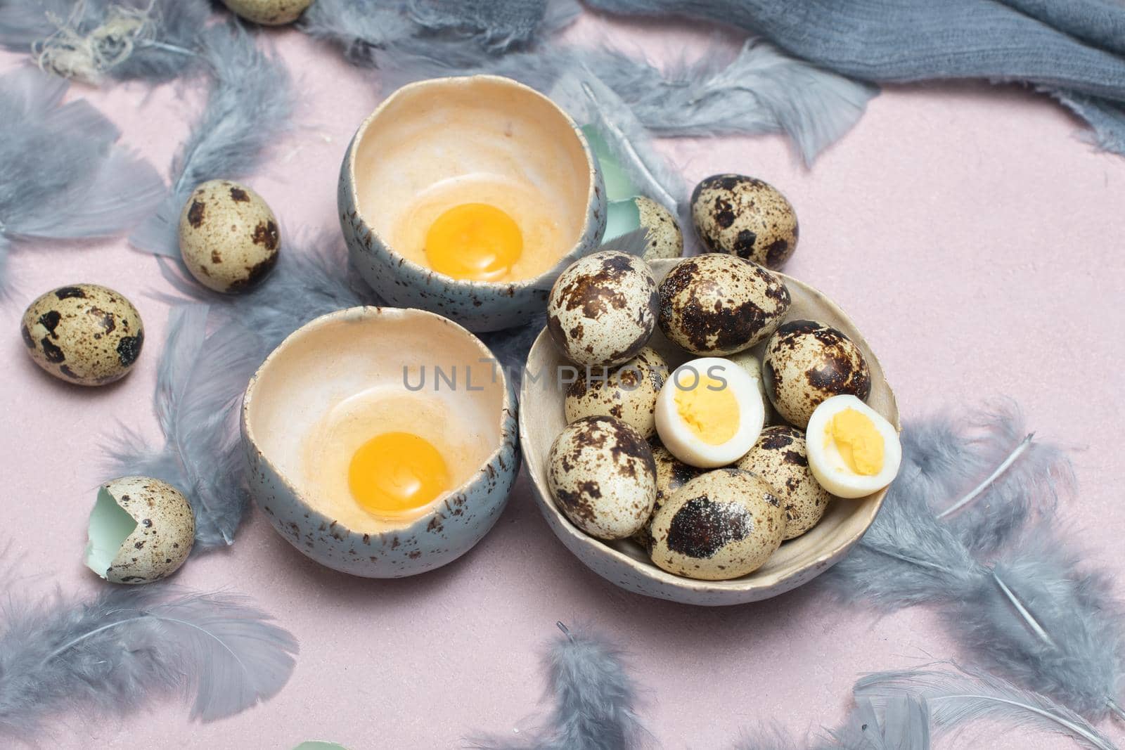 quail eggs in ceramic vases, gray feathers on the table, easter still life, natural food, diet and antioxidants, dark key and shallow depth of field. High quality photo