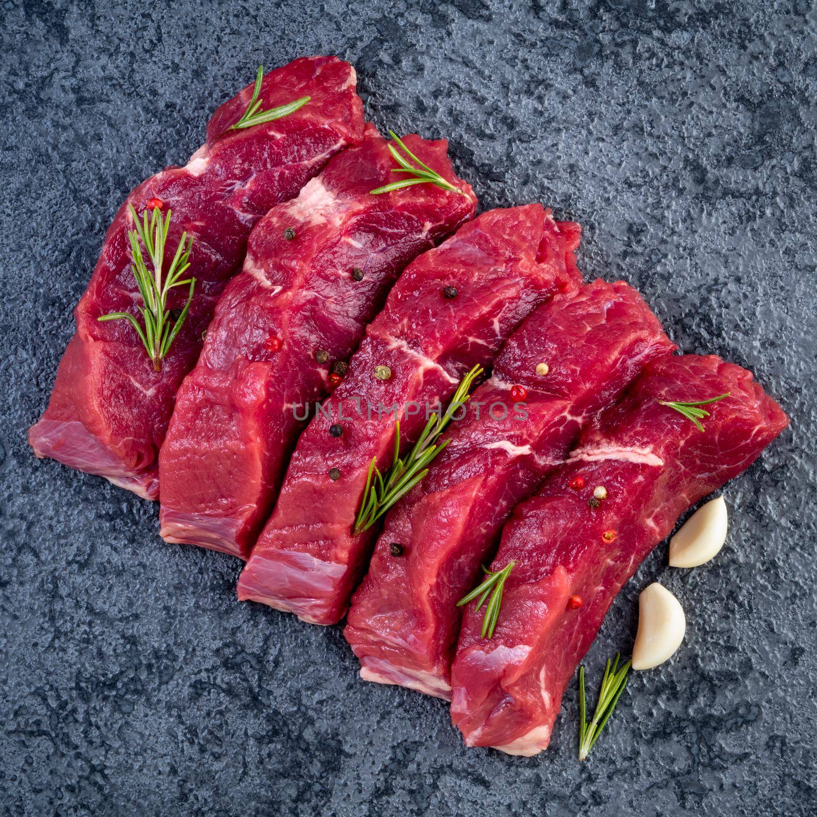 Raw meat, beef steak with seasoning on black stone table, top view by NataBene