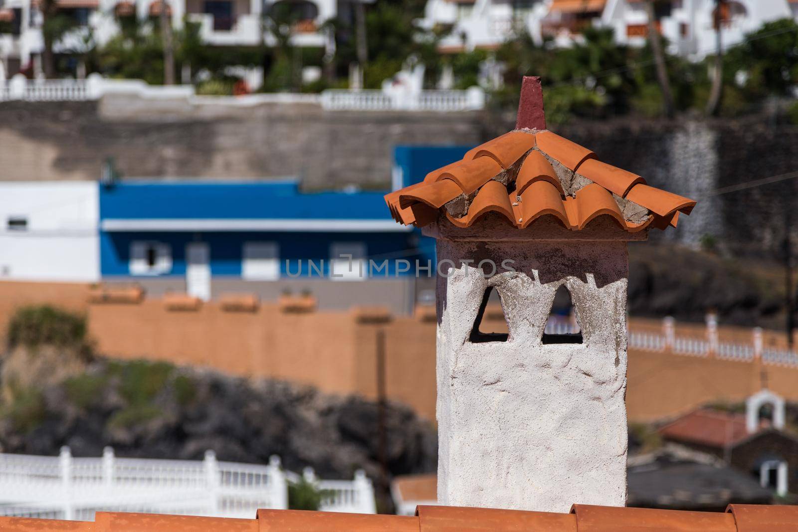 Orange shingle roof with chimney in mediterranean style, buildings at the background