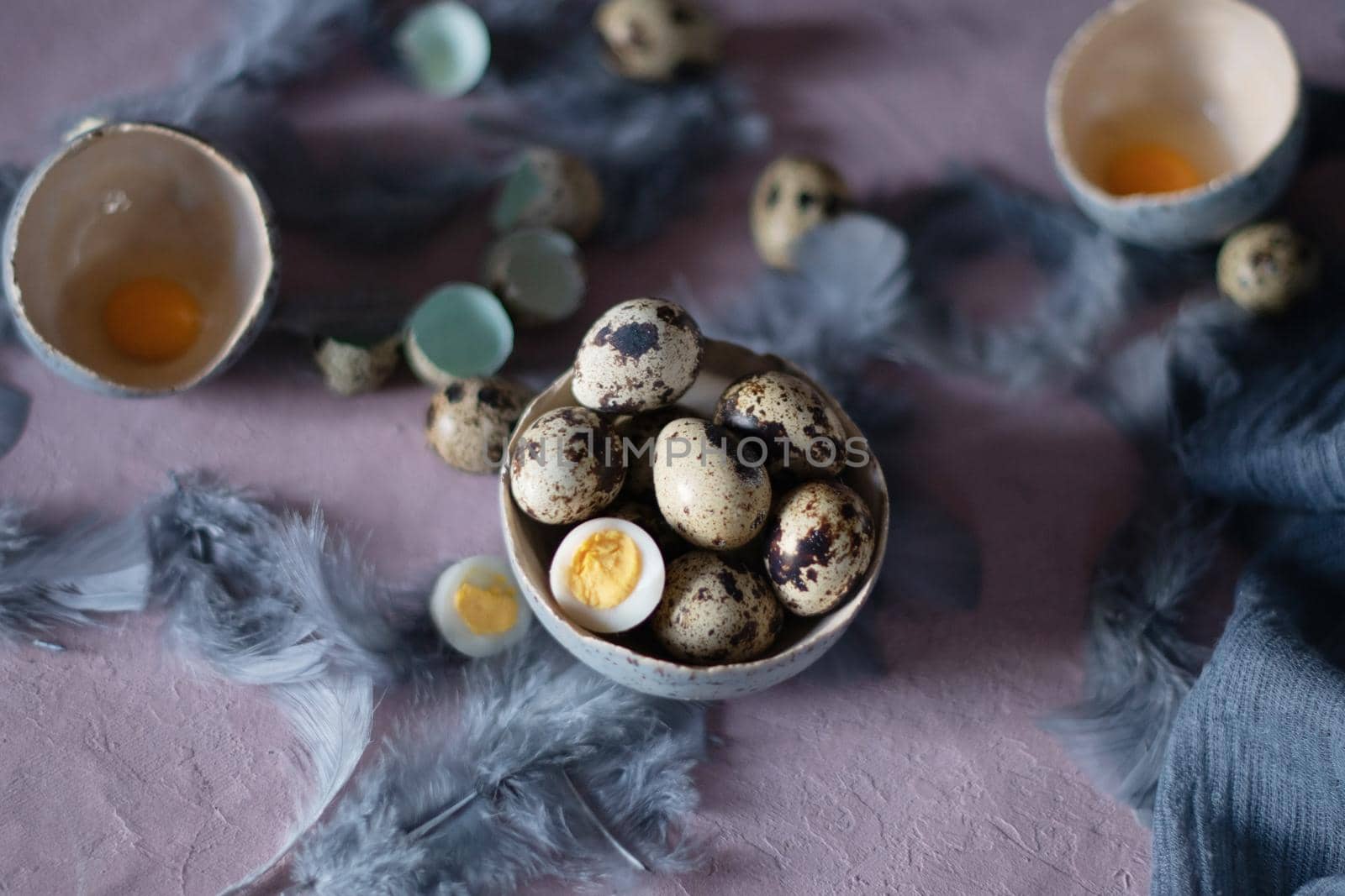 quail eggs in ceramic vases, gray feathers on the table, easter still life, natural food, diet and antioxidants, dark key and shallow depth of field. High quality photo