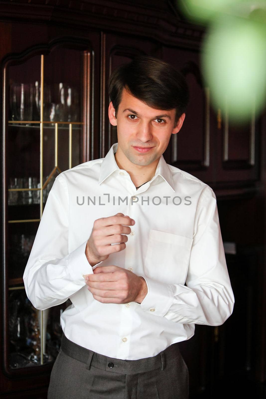 Groom in a white shirt fastens buttons