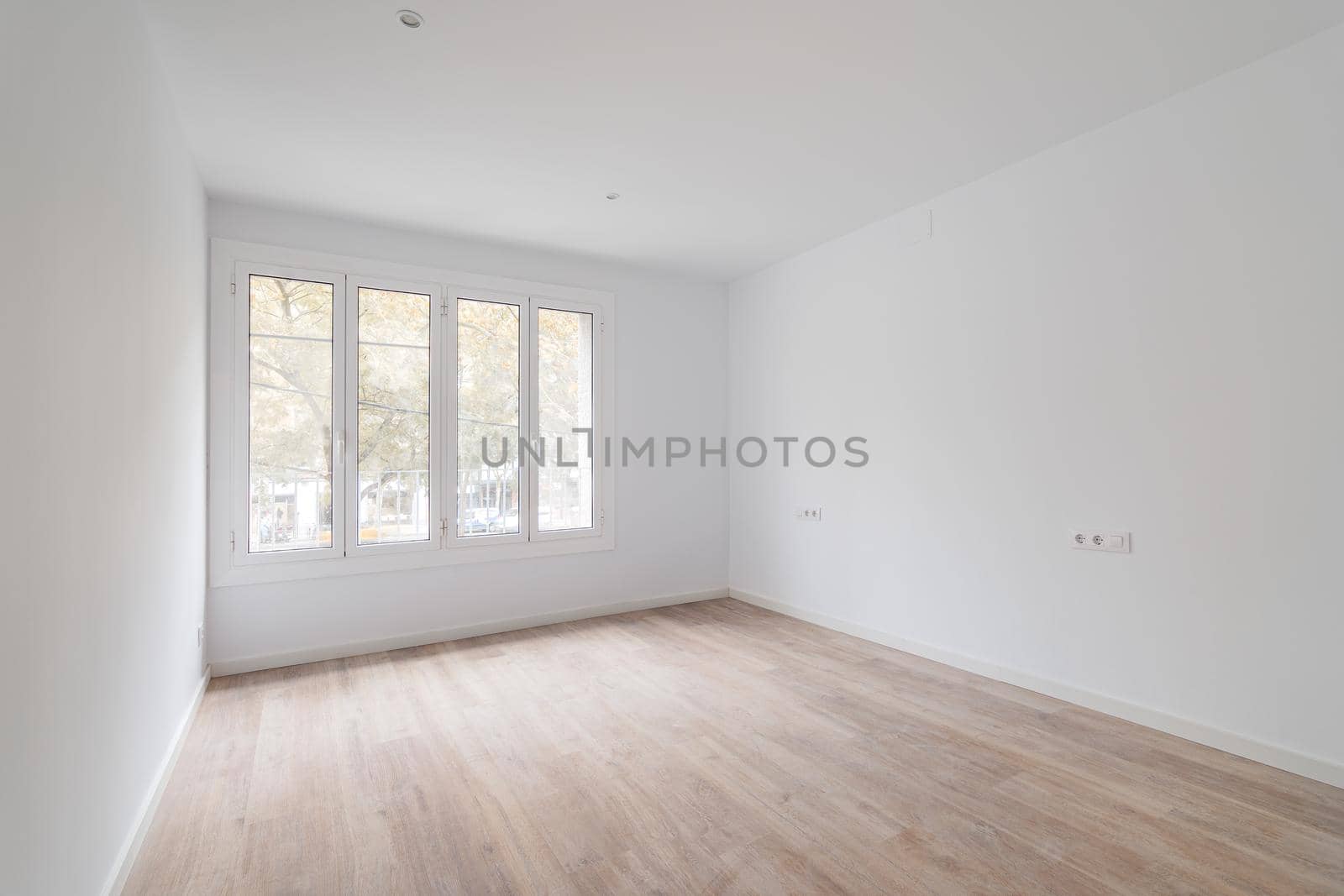 Empty dusted room after renovation with white walls, windows and wooden floor.