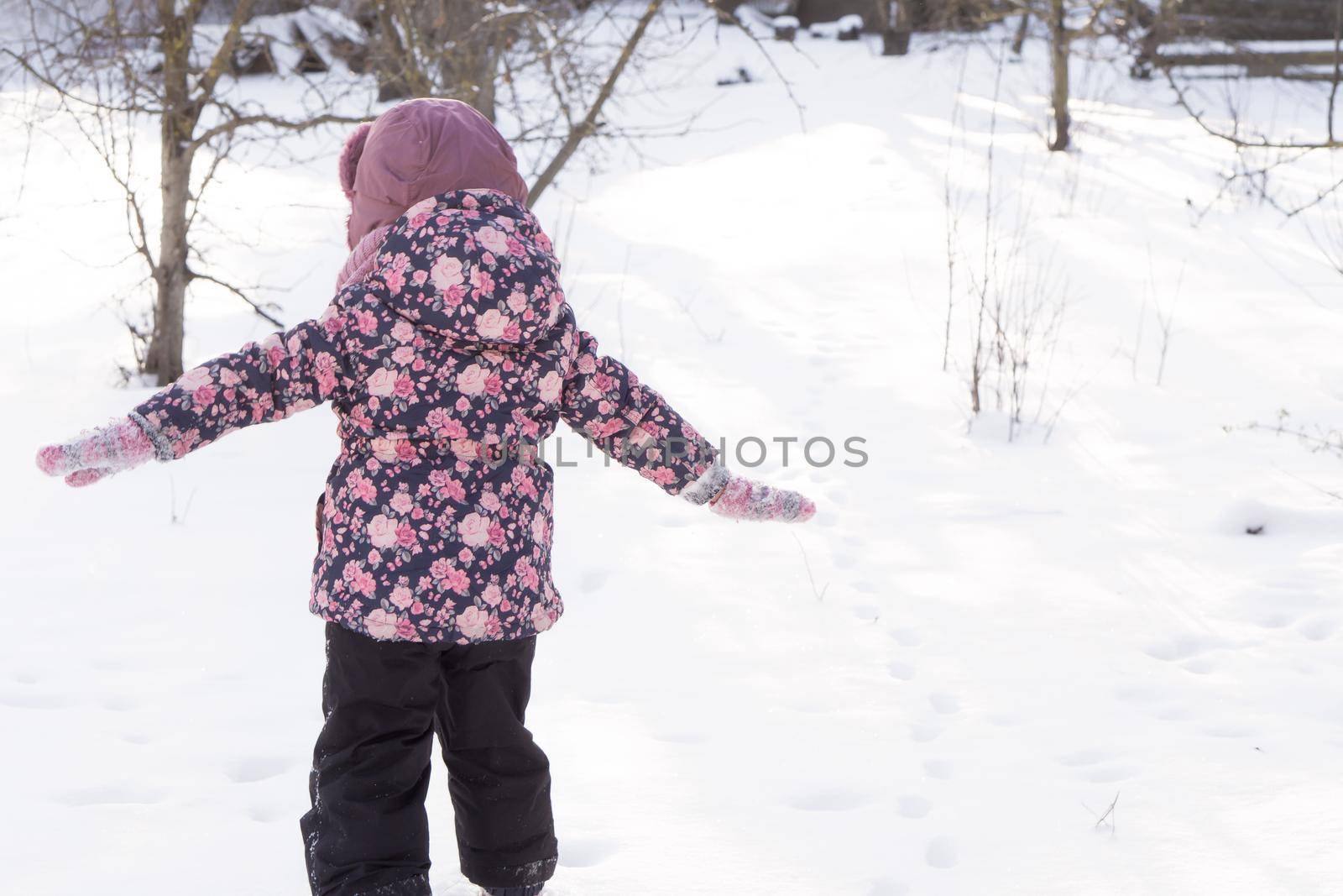 Winter, family, childhood concepts - authentic little preschool minor girl walking in snowy frosty cold weather day in park. happy little kid have fun run Straightened their arms like plane outdoors by mytrykau