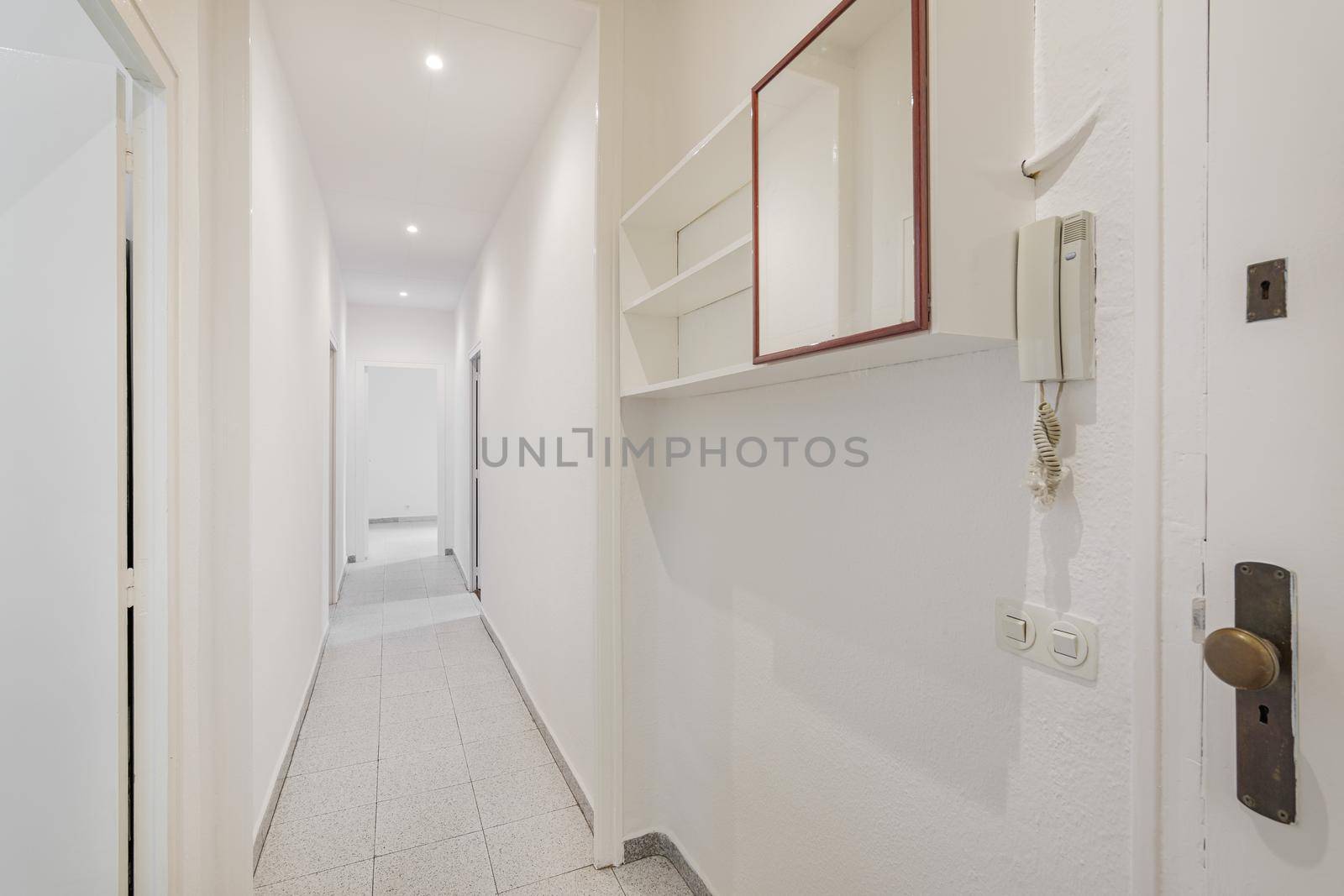 White empty corridor with doors and floor tiles in an old apartment