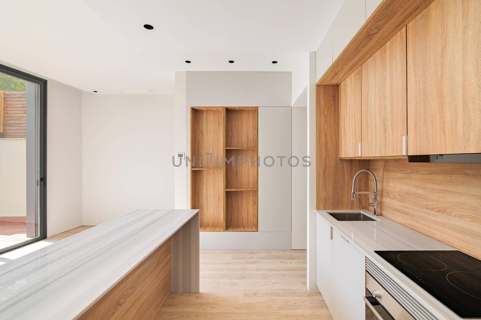 Modern kitchen interior with island and wooden furniture. Empty interior of bright refurbished apartment