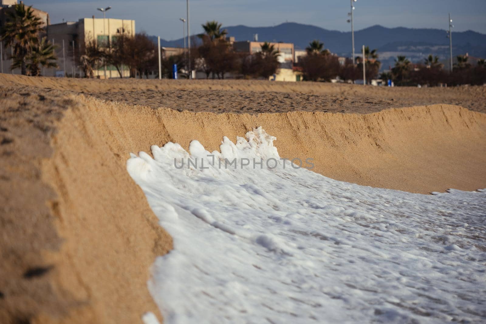 Foam wave of the sea on sharp edge of sandy beach on the sunset. Selective focus. by apavlin