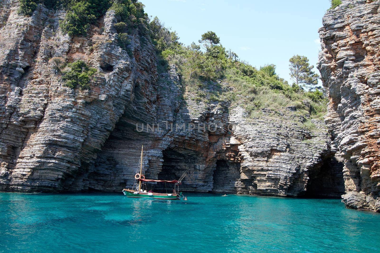 Blue lagoon with fishing boat and adriatic cliffs