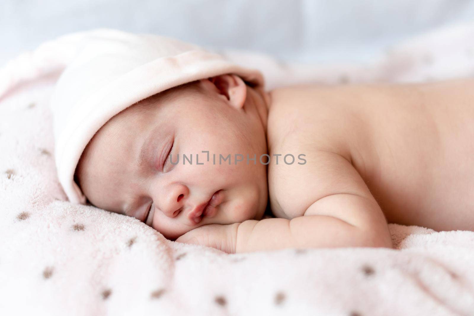 Childhood, care, motherhood, health, medicine, pediatrics concepts - Close up Little peace calm naked infant newborn baby girl in pink hat sleeps resting take deep nap laying on tummy on soft bed