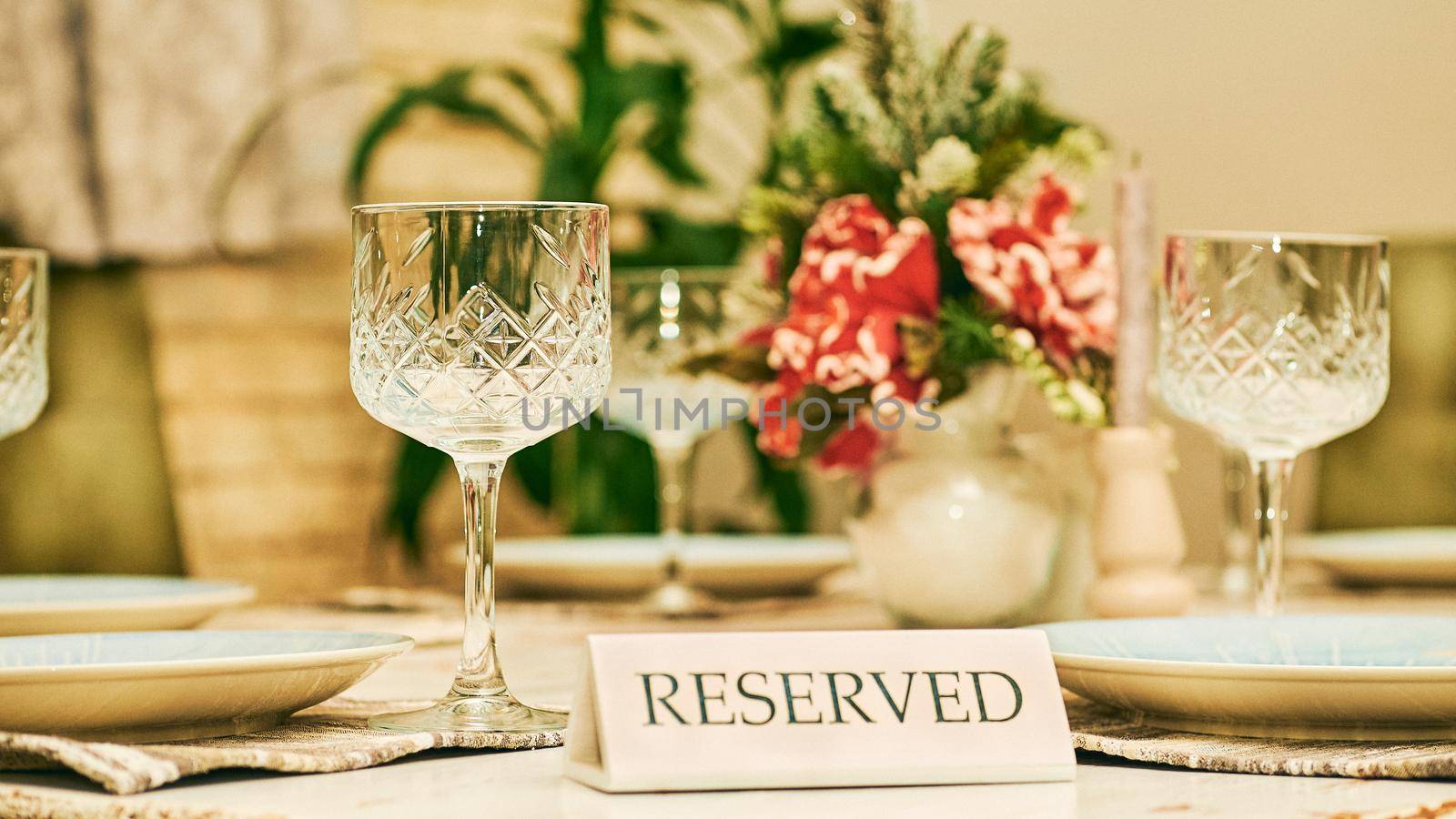 a place where people pay to sit and eat meals that are cooked and served on the premises.Reserved table in a restaurant with glasses and a red flower.