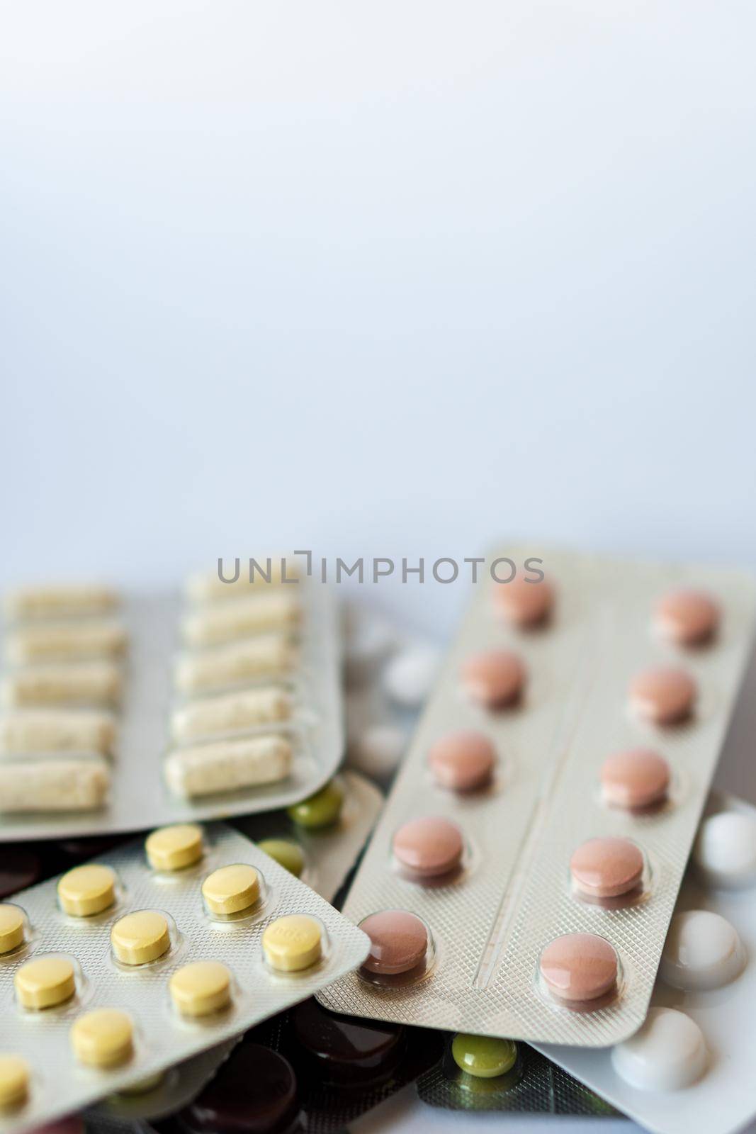 Medicine and pills. Multi-colored medicines on a white background close-up. Plate with multi-colored tablets on a white background. Multi-colored tablets that spilled from an inverted jar onto a white surface