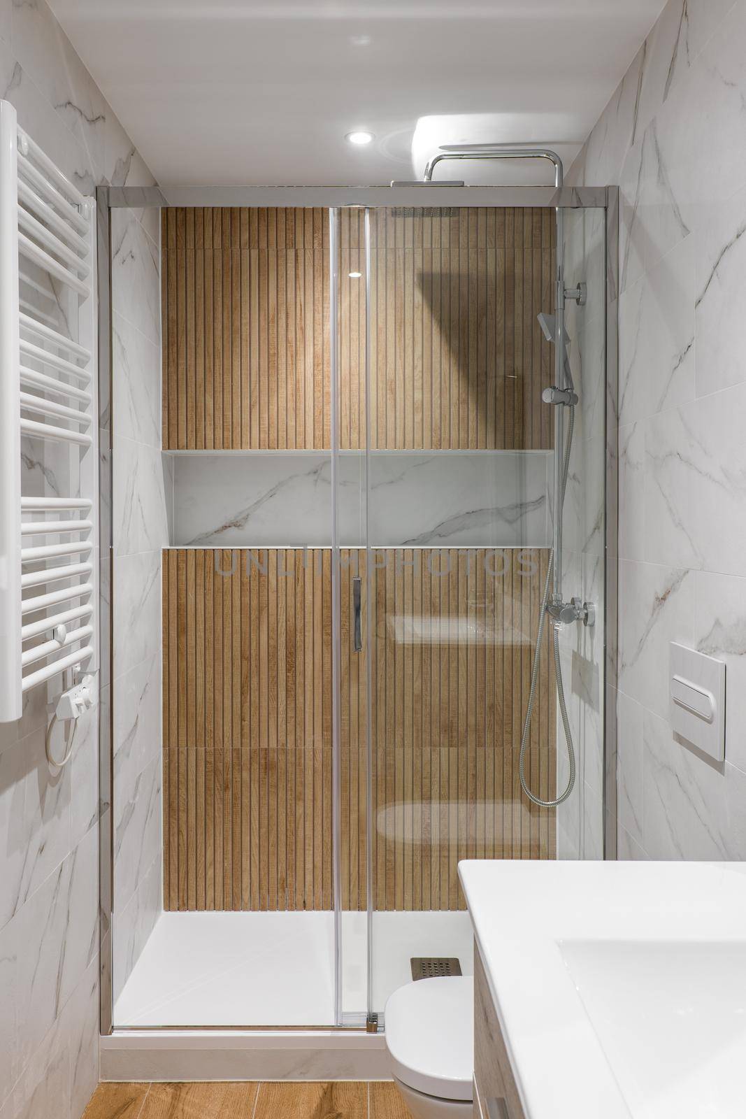 Shower zone with wooden finishing and glass door. Interior of modern refurbished bathroom by apavlin