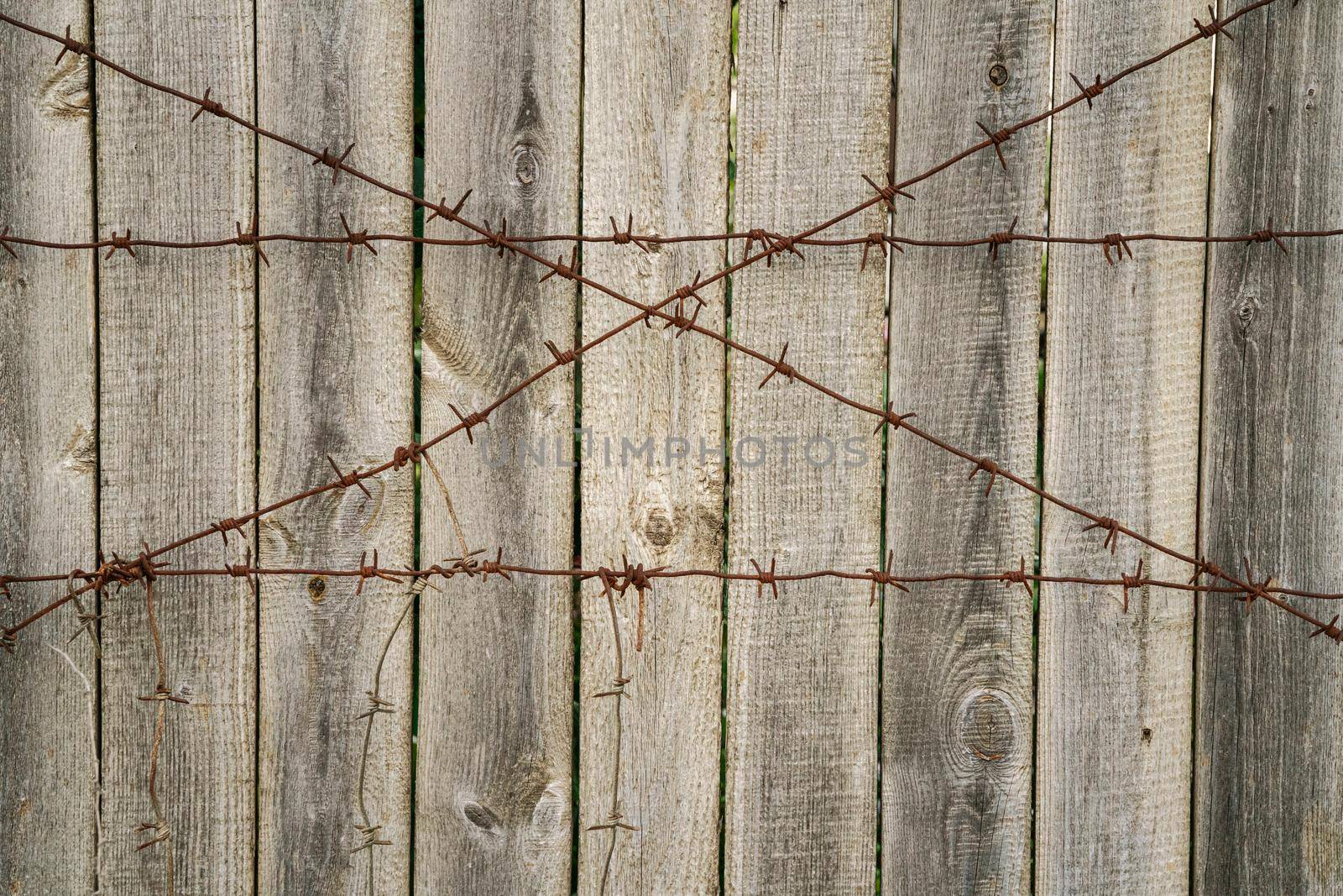 Background with a double row of barriers - from barbed wire and solid fence. Hard background in monochrome tones. Shallow DOF, selective focus