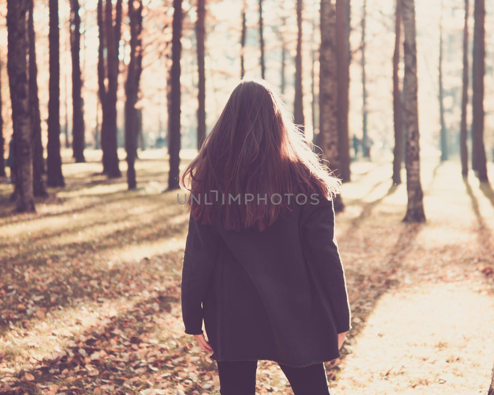 teen girl standing in the autumn Park with her back to the camera, turns on the spot. Woman with long hair standing outdoors.