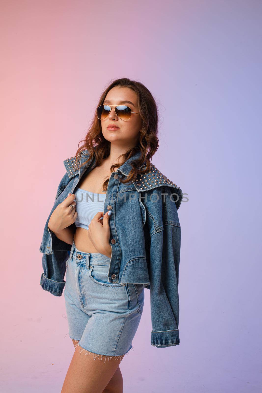 a woman in denim shorts, sunglasses in the studio on an interesting beautiful background by StudioLucky