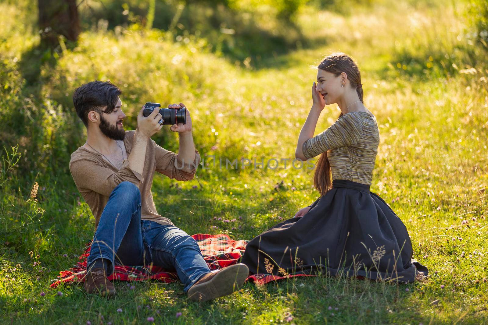 the guy photographs his girlfriend with a camera in a summer park