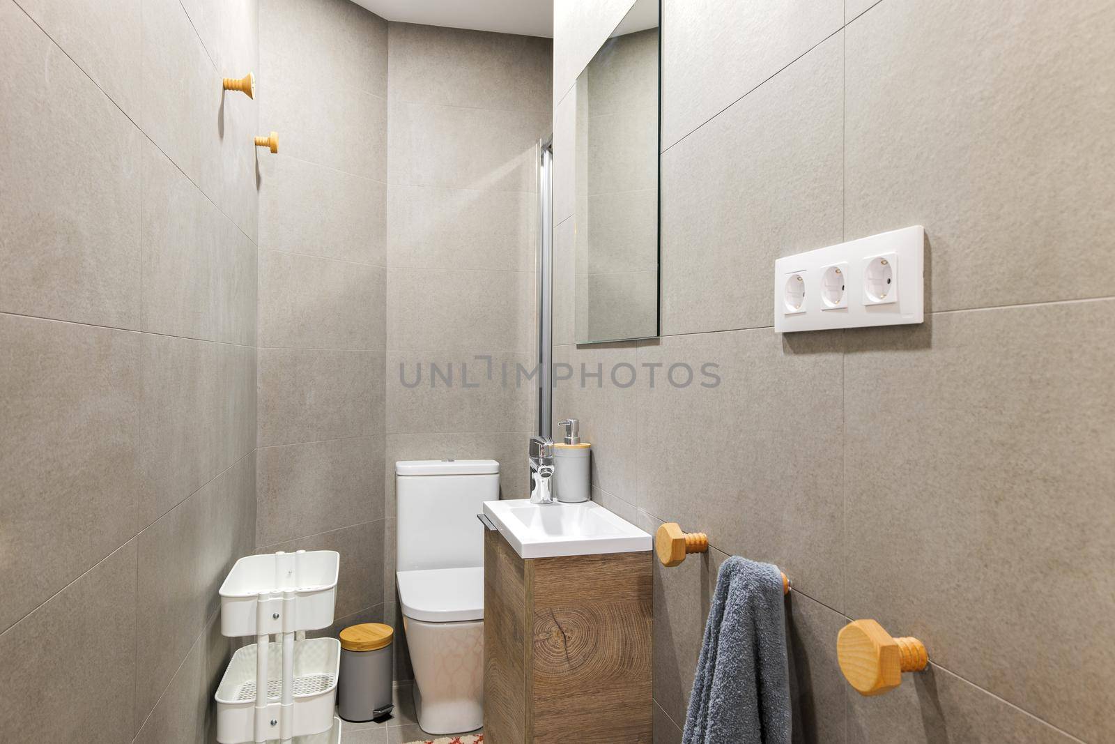 Photo of a narrow bathroom with floor tiles resembling wood and glass shower enclosure