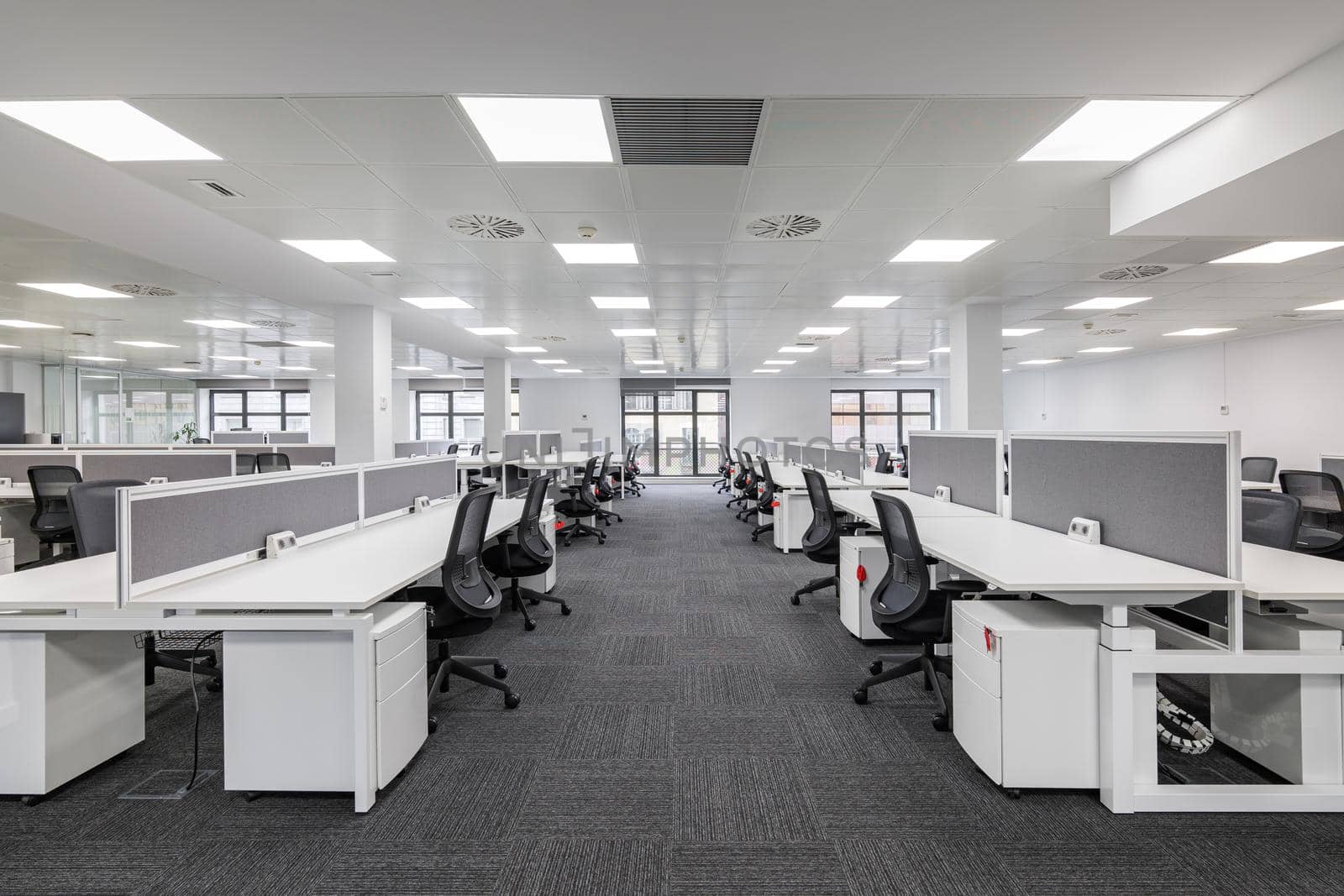 Modern corporate open office in minimalist modern design in whites and greys, empty office workstations