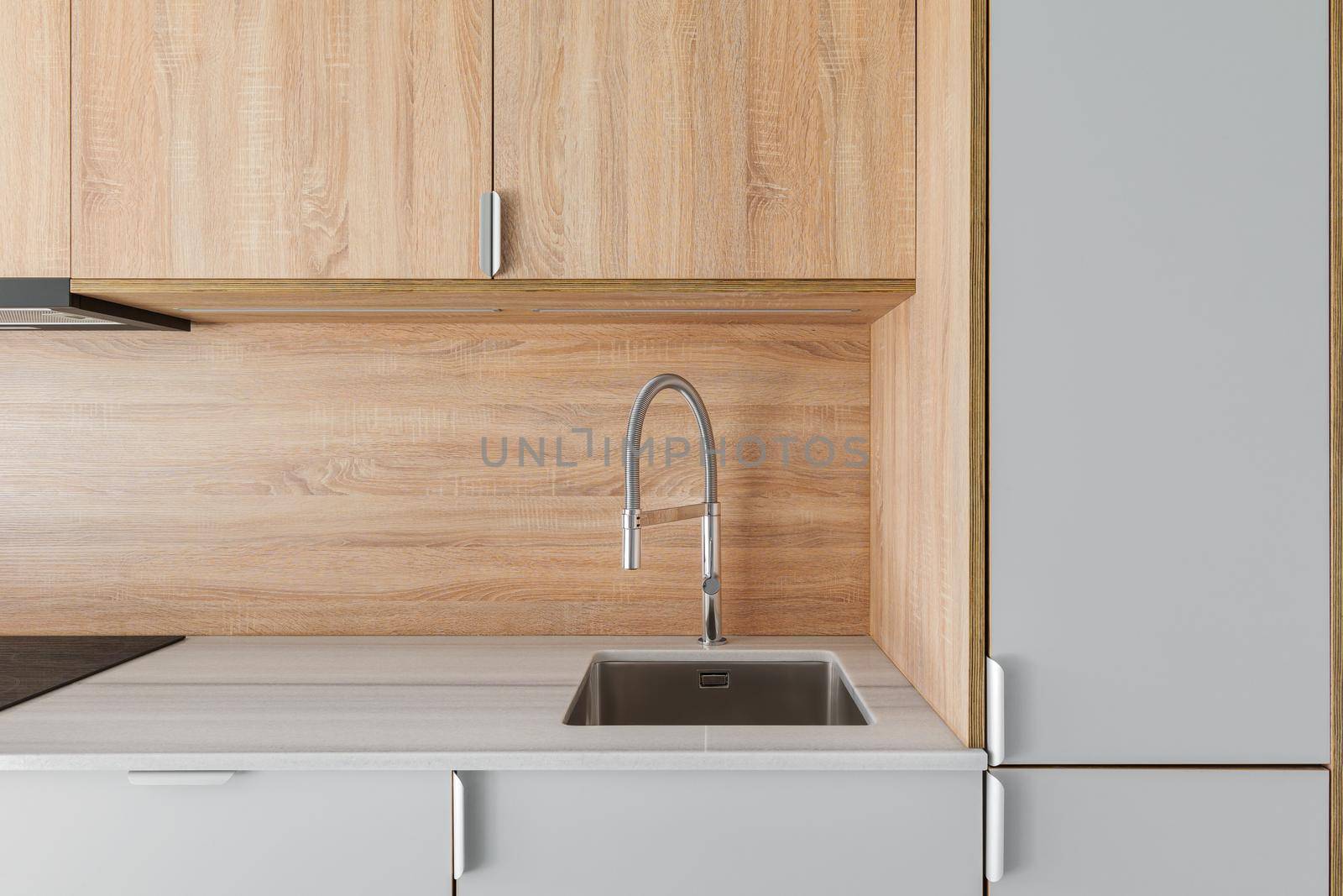 Close-up of metal sink and faucet at contemporary minimal kitchen. Wooden furniture at empty refurbished apartment by apavlin