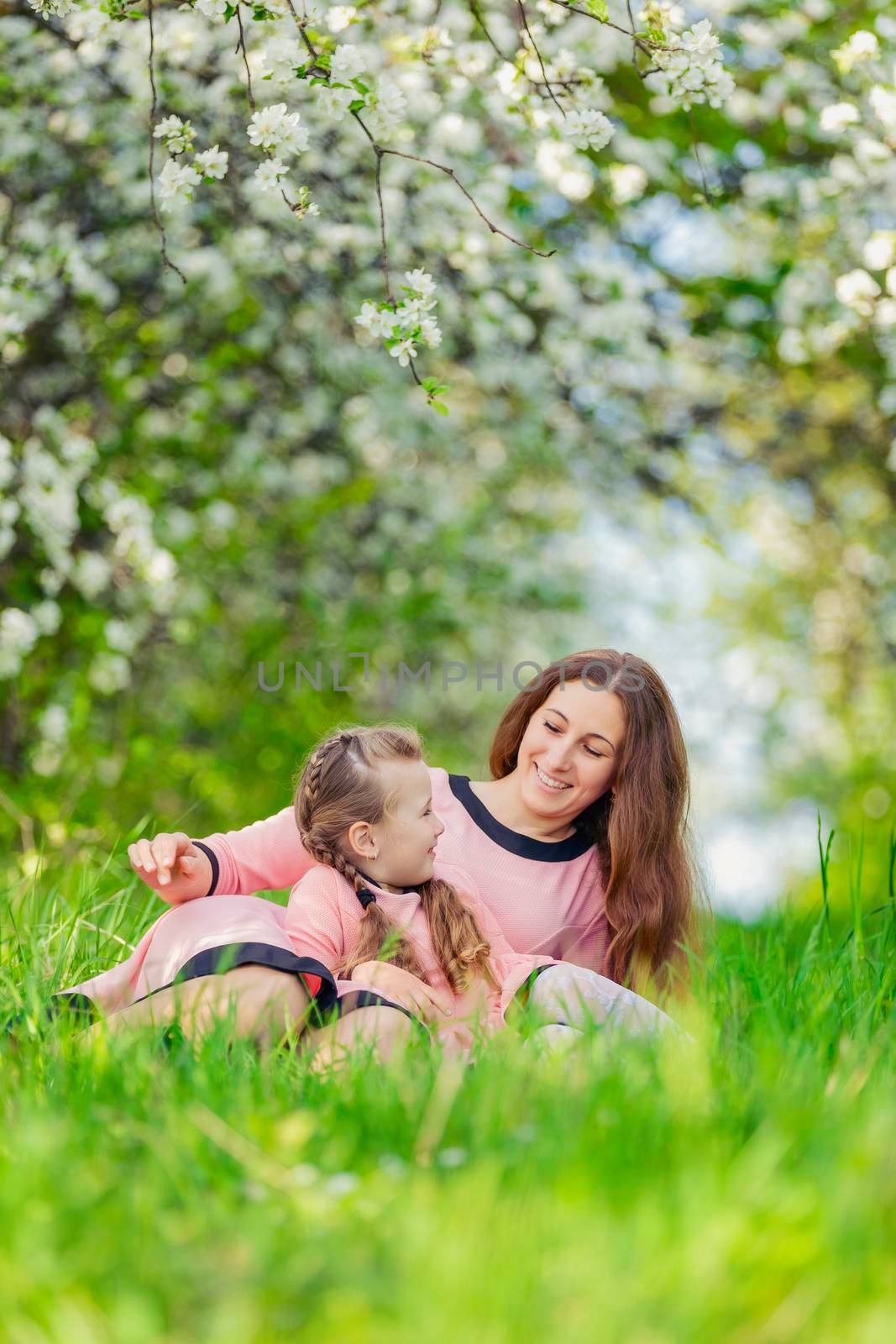 mother and daughter in identical dresses lie in the grass