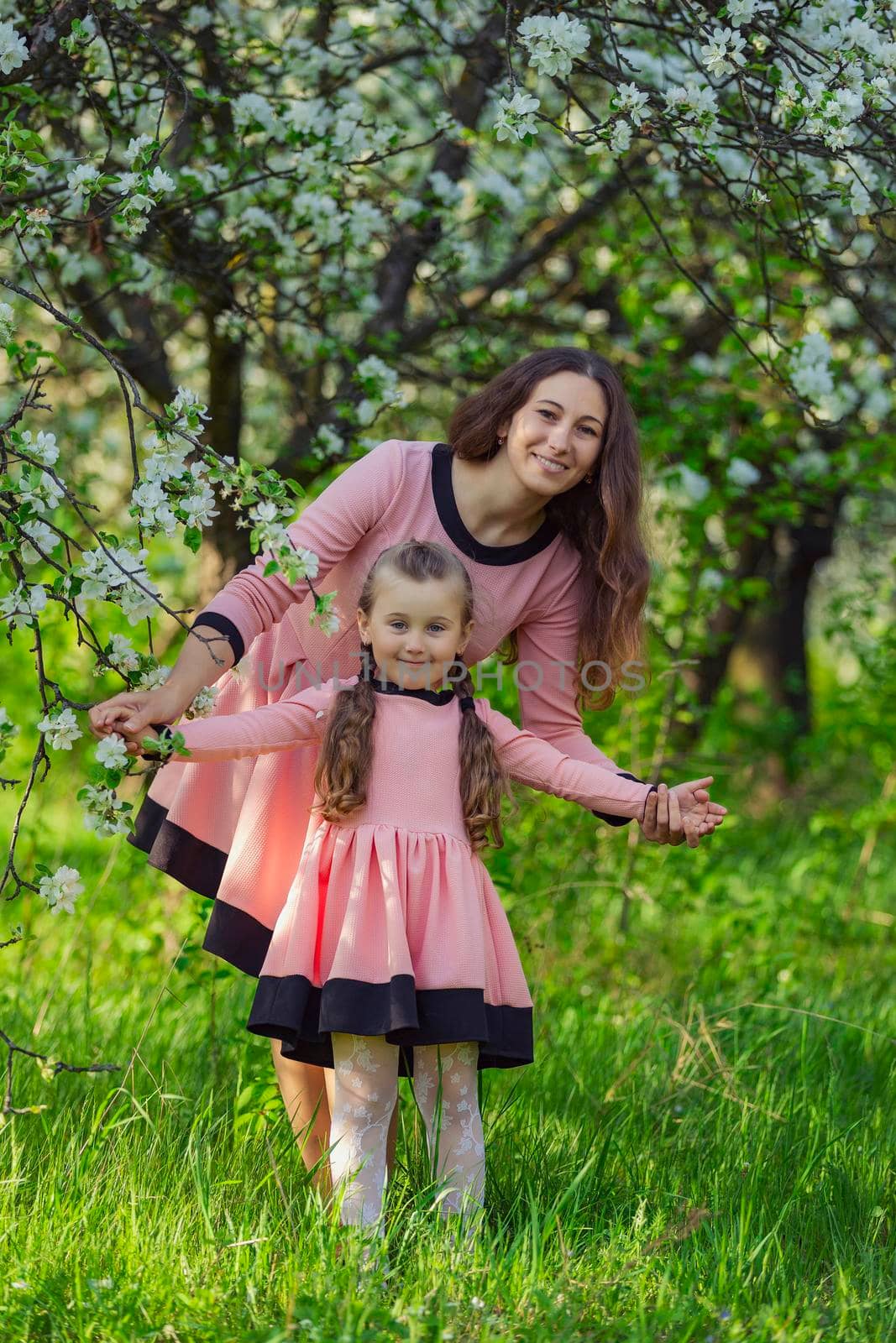 mother and daughter are walking through the blooming garden