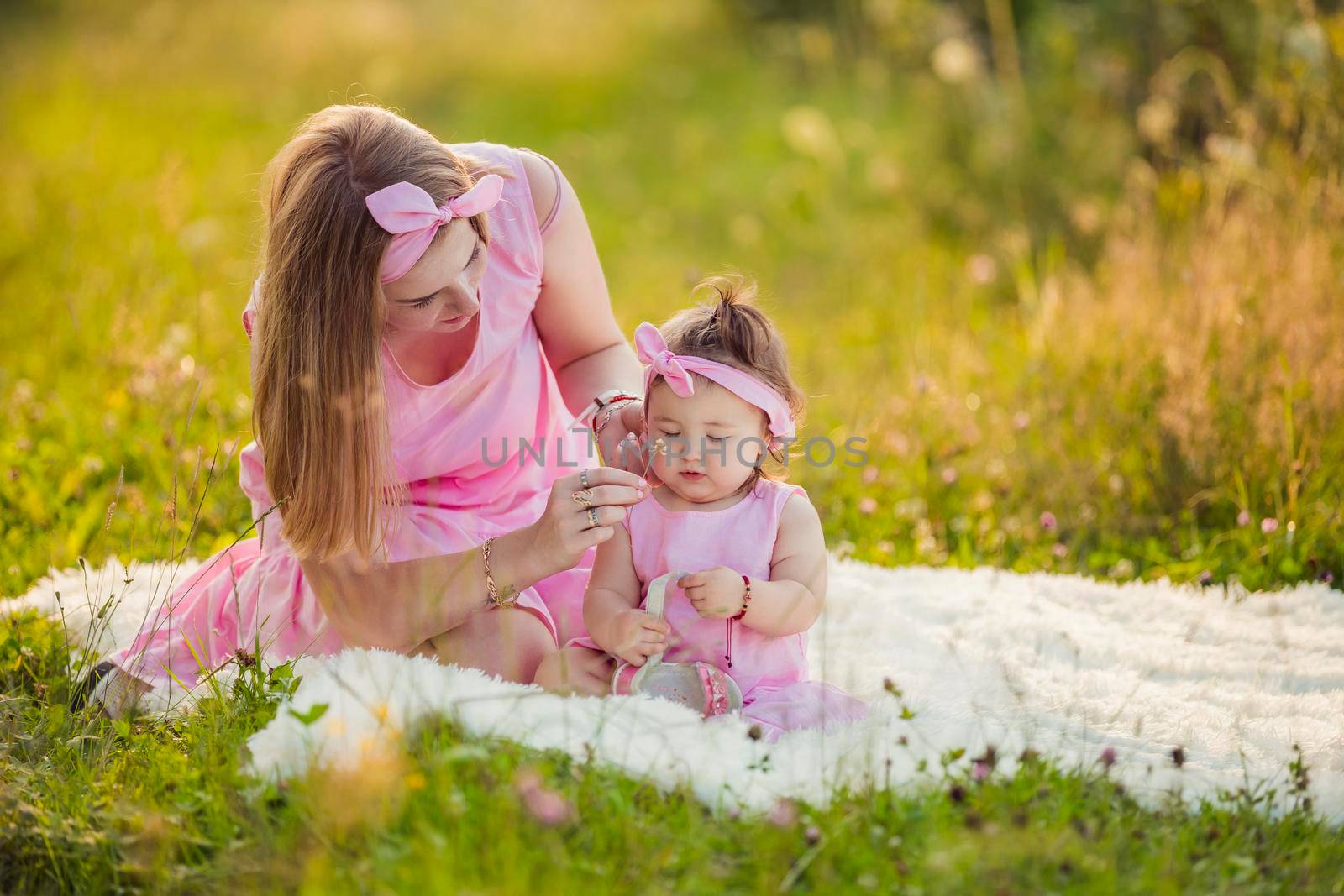 mother and daughter are sitting on a blanket in the summer garden