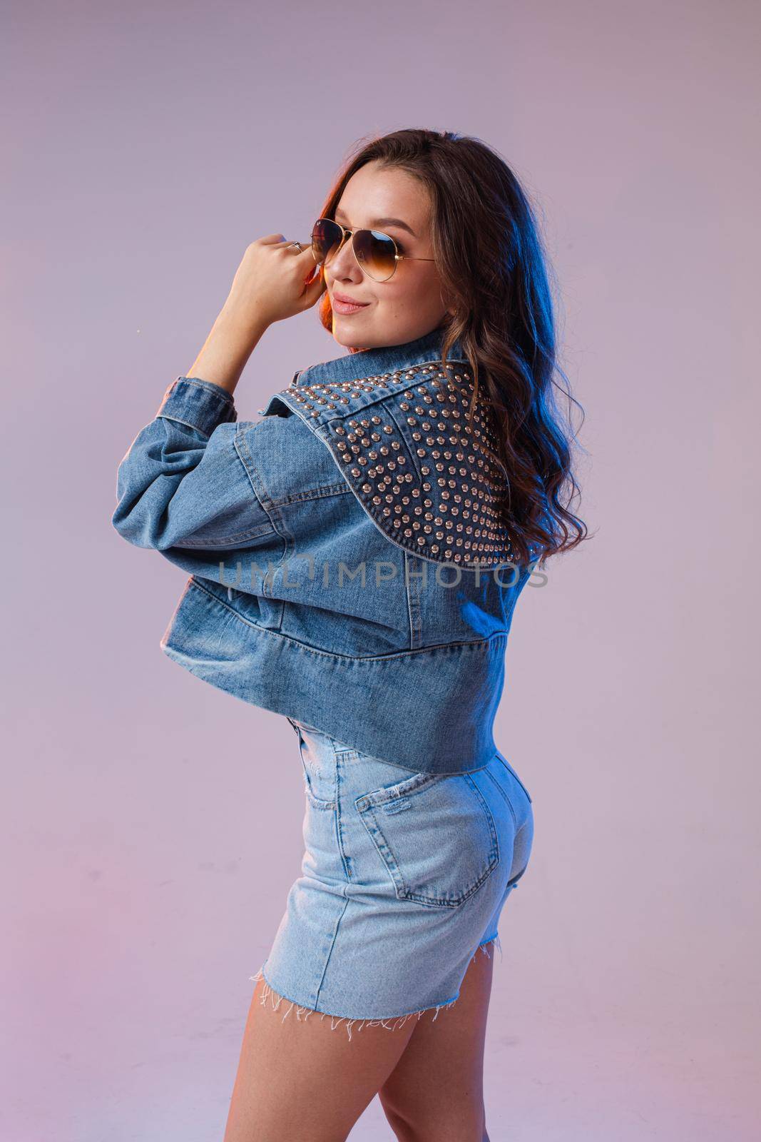 a woman in denim shorts, sunglasses in the studio on an interesting beautiful background.