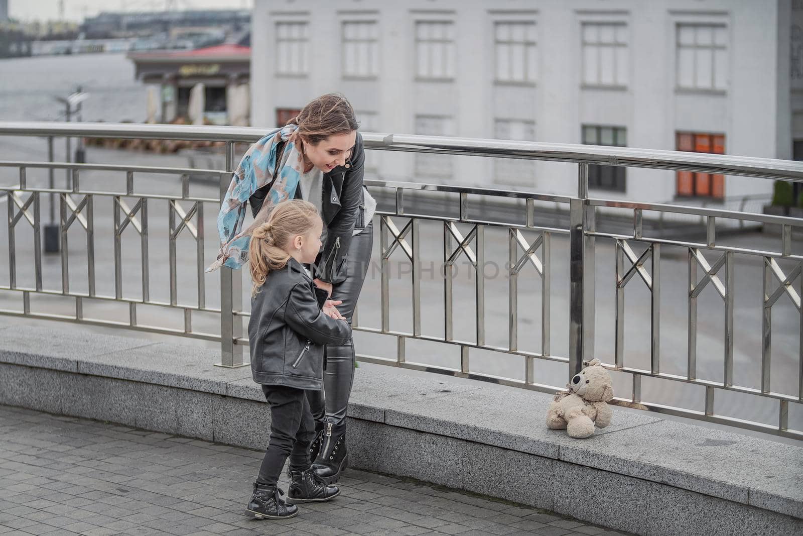 mother and daughter are walking around the city near the iron railings