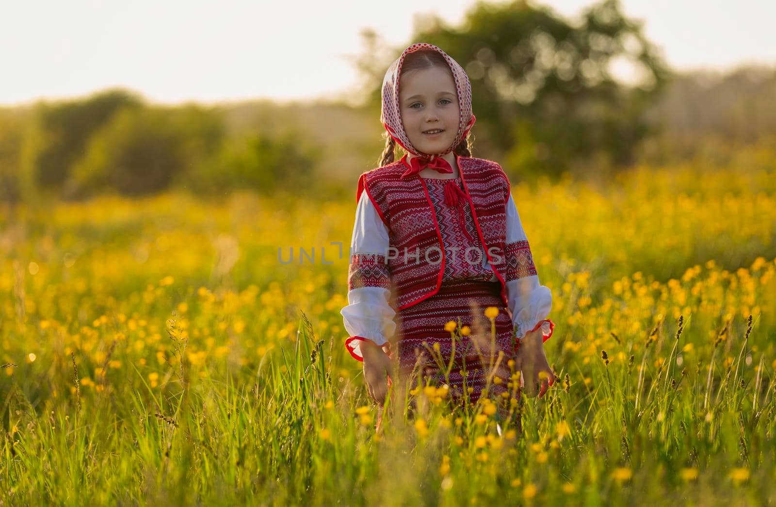 portrait of a little girl in a red suit among yellow flowers