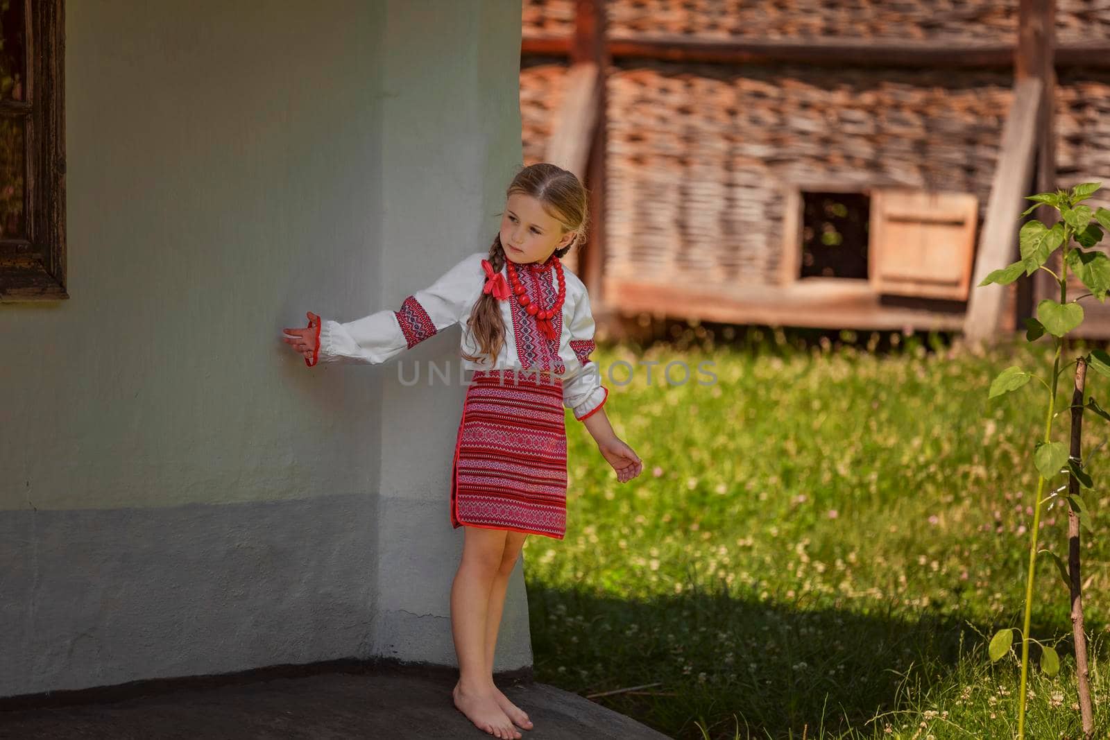 child in a traditional Ukrainian costume is playing in the yard