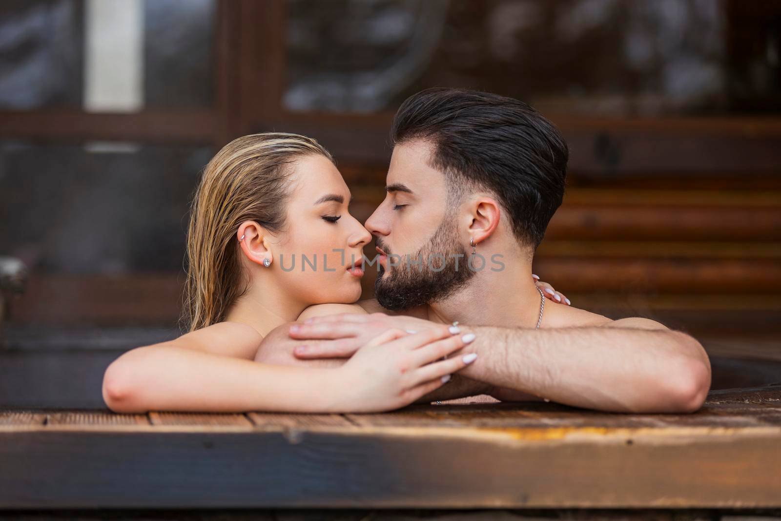 portrait of a couple kissing in a tub of water