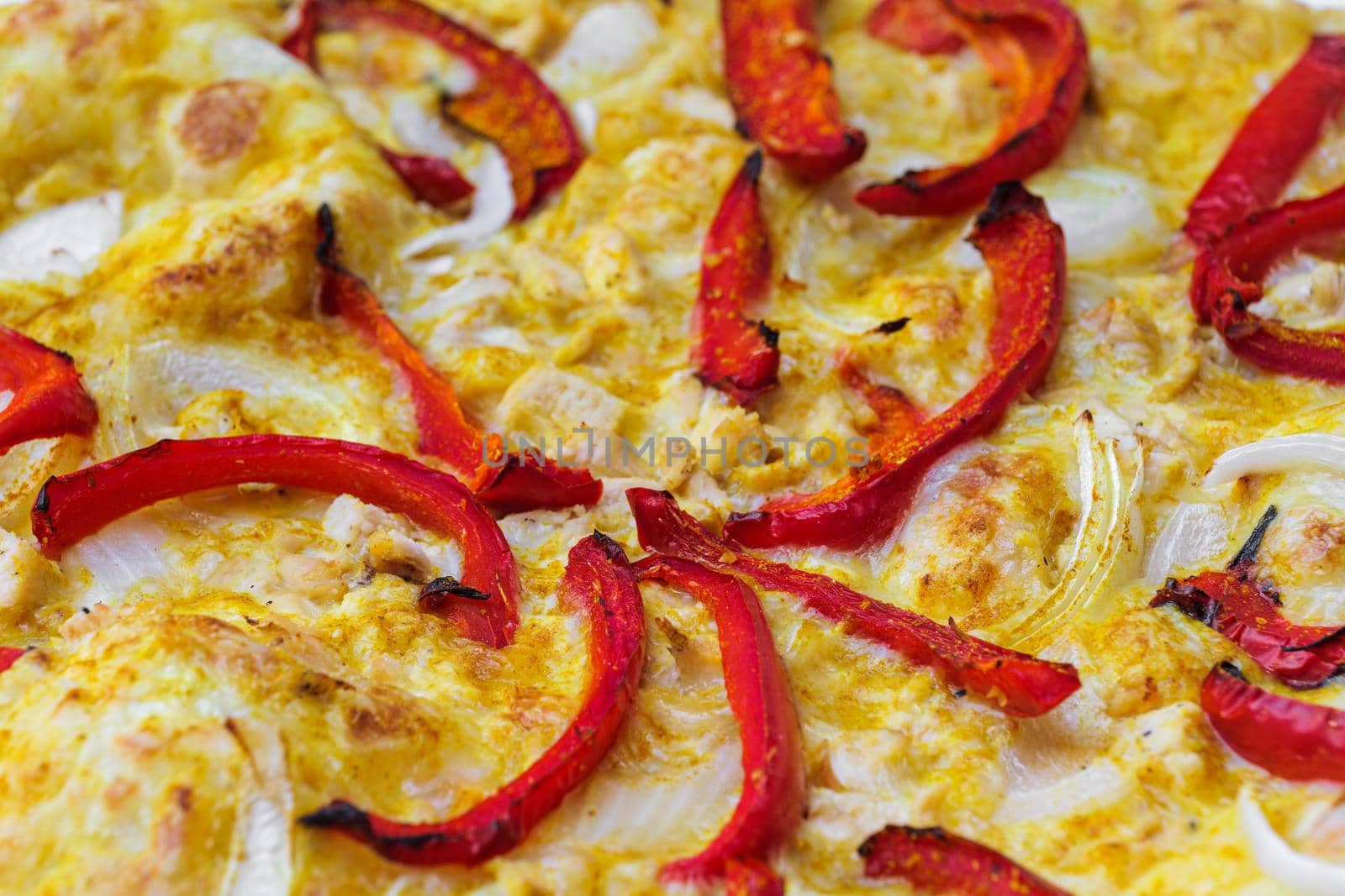 Close-up of pizza topped with red pepper, onion and yellow curry sauce. Macro shot of delicious products. Selective focus.