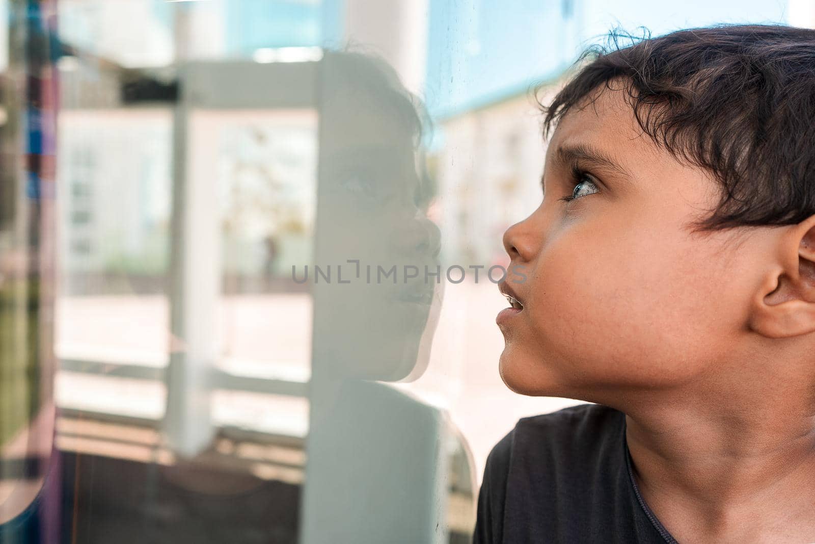 Latino boy seeing his reflection in a glass outdoors in Managua, Nicaragua. Concept of self discovery in childhood.