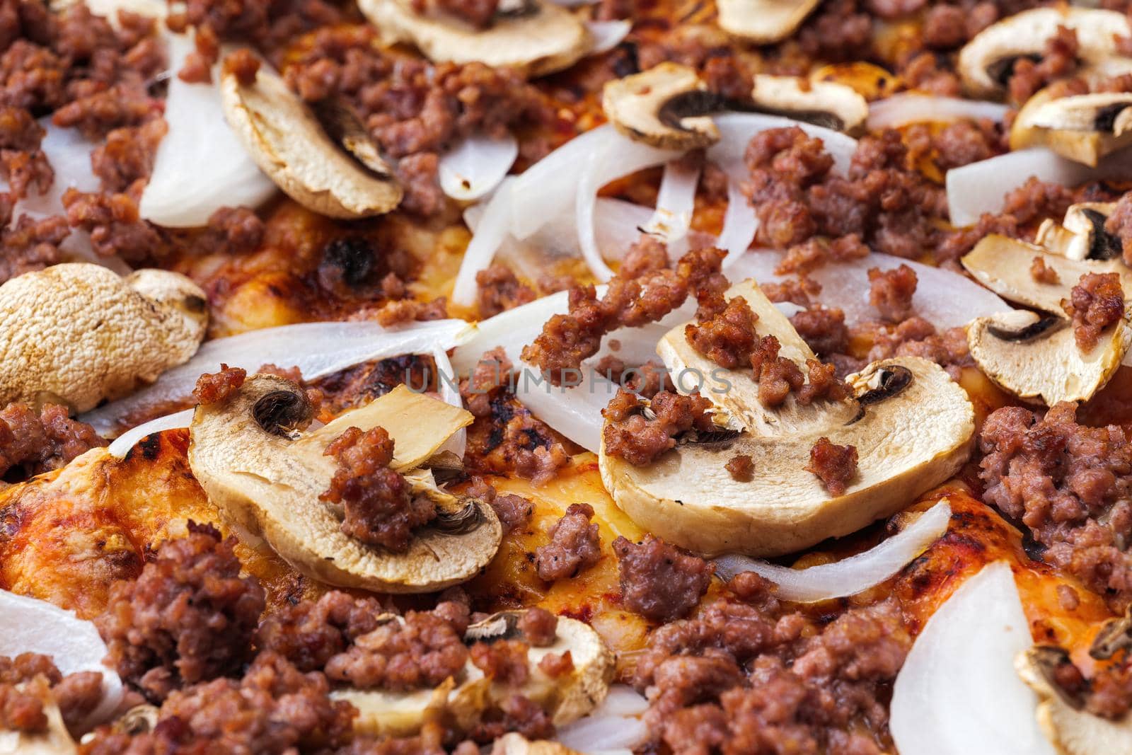 Close-up of pizza topped with mushrooms, onion and chopped meat. Macro shot of delicious products. by apavlin