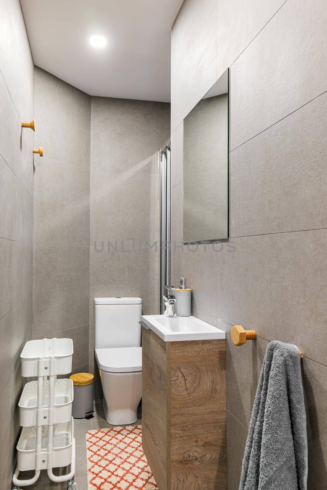 Narrow bathroom with, toilet, small washbasin, decorated with gray tiles. Contemporary style interior after home renovation. by apavlin
