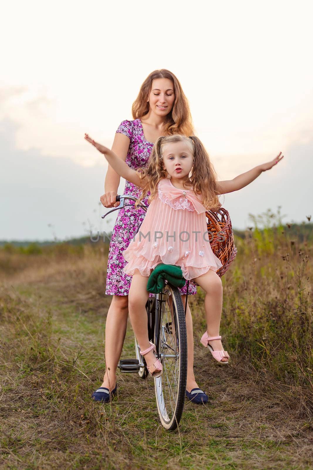 mom rides her daughter on a bike by zokov