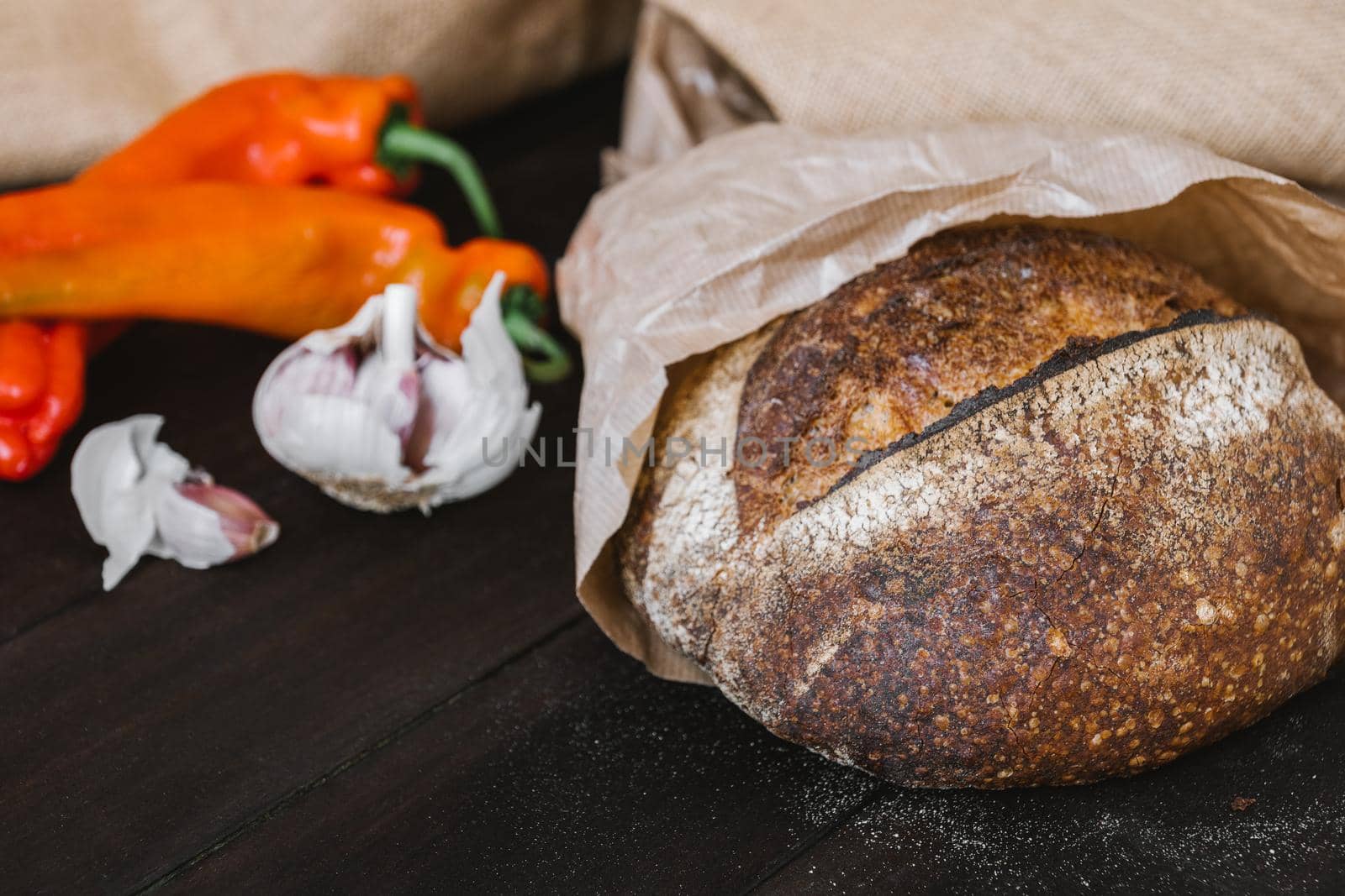 Artisan sourdough bread on wooden table with vegetables. Freshly baked round loaf of sourdough bread by apavlin