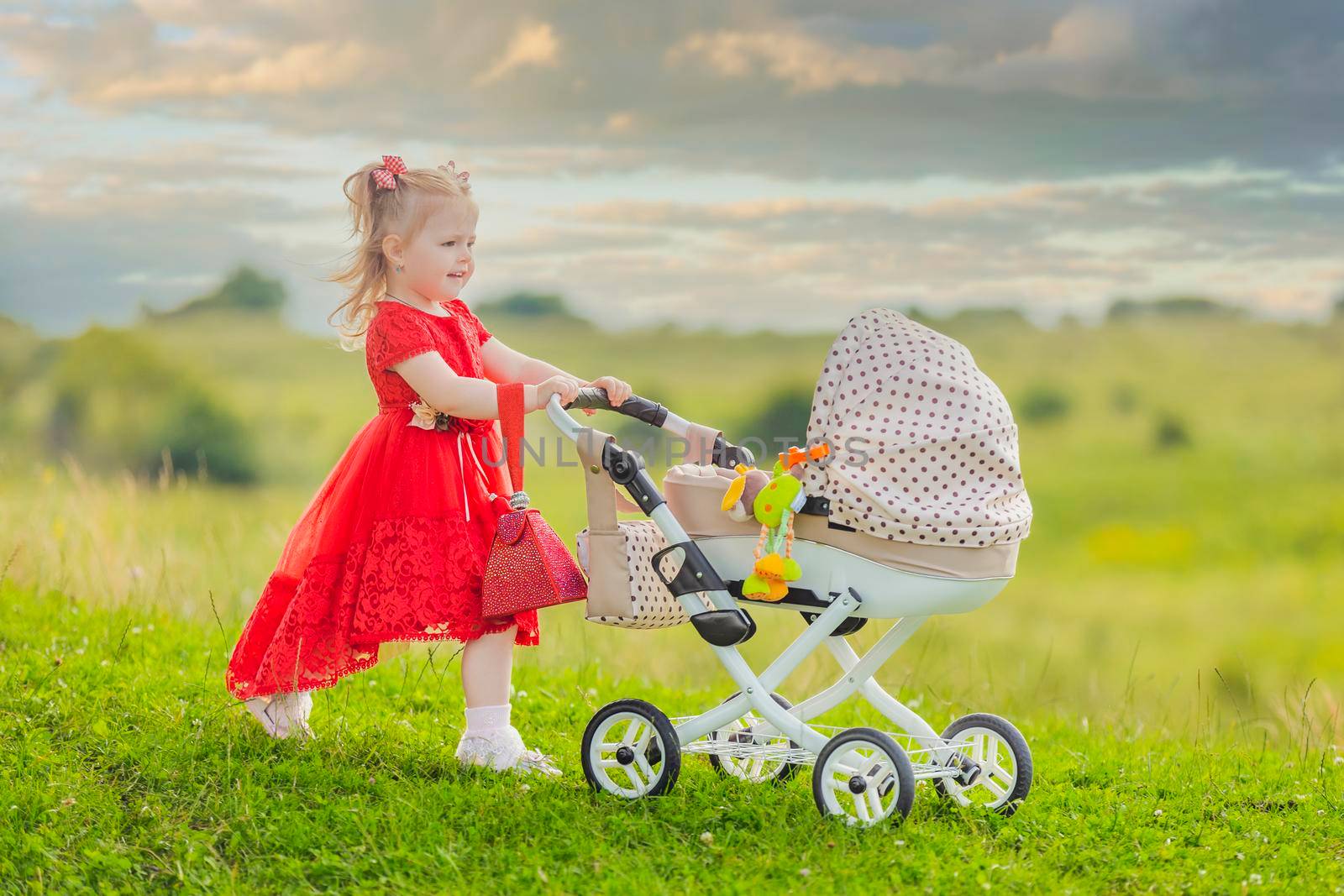 girl with a toy stroller walks in nature