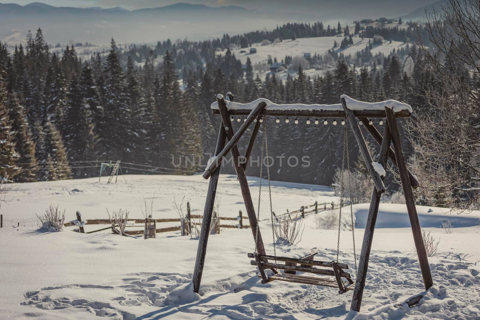wooden swing against the backdrop of forest snow-capped mountains