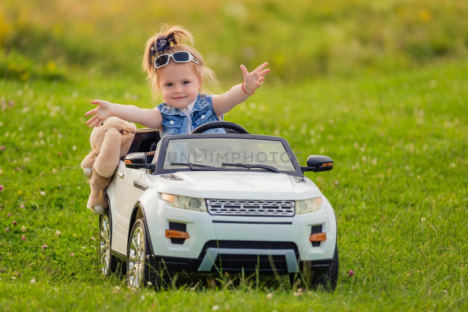 girl rides in her white car on green grass