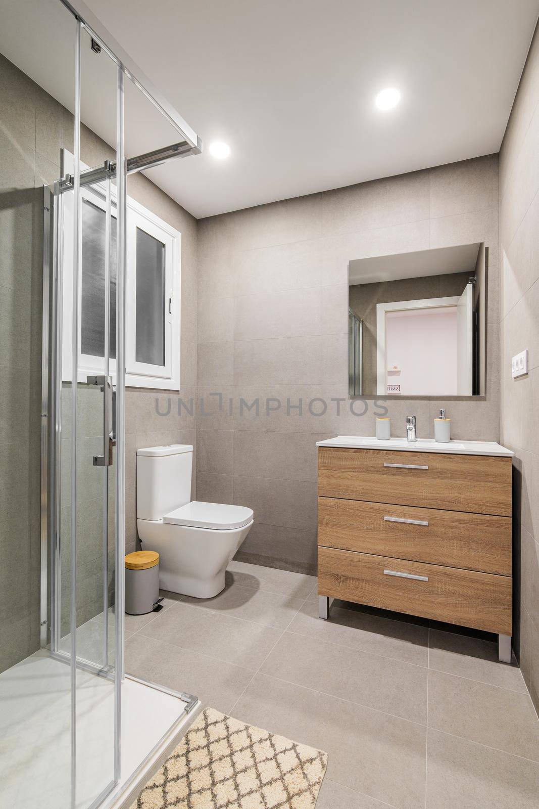 Modern refurbished bathroom with shower zone, toilet, wooden base with white sink and mirror