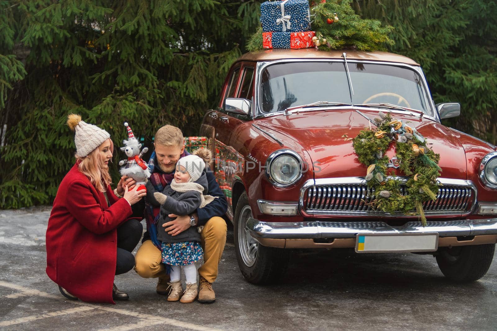 family near retro car with gifts in the parking lot near the park