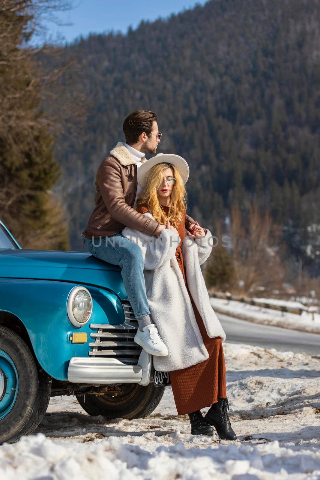 couple sitting in winter near a retro car