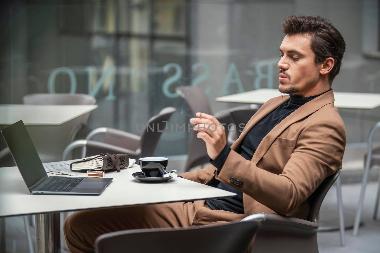 a man in a suit sits at a table and smokes