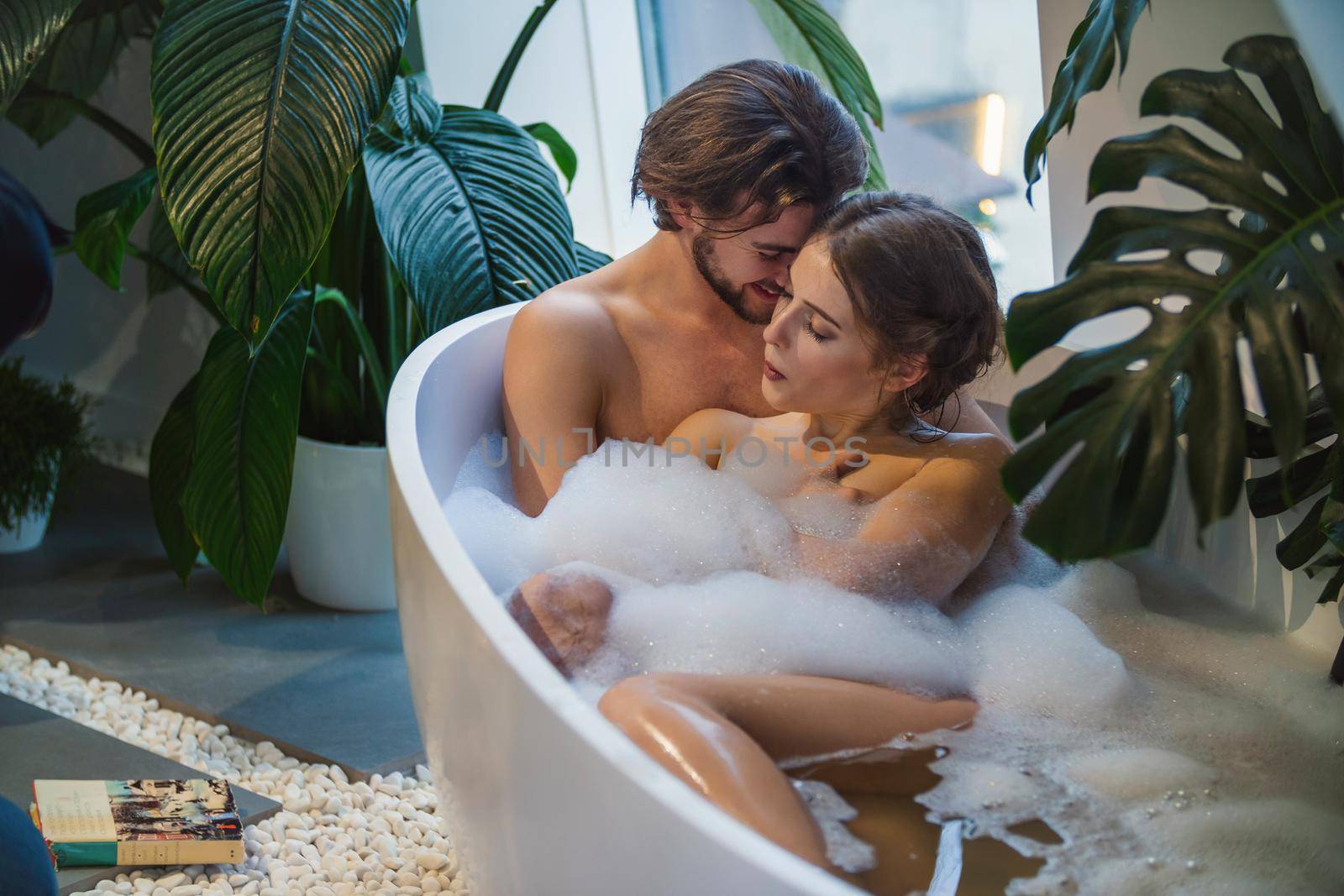 beautiful couple lies in a bath with foam
